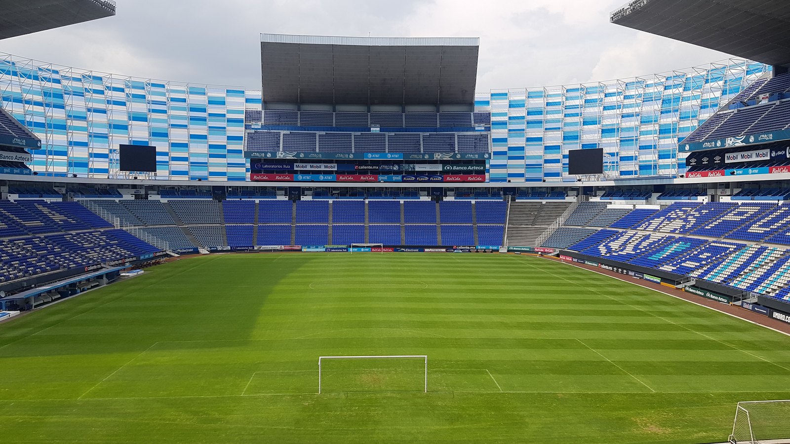 Interior del Estadio Cuauhtémoc: graderío, pasto y portería, a color, sede de Puebla-Atlante