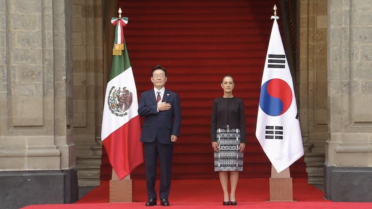 Lee Jae-myung y Claudia Sheinbaum en la escalinata de Palacio Nacional, entre las banderas de México y Corea