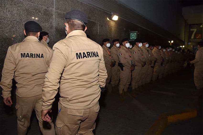 Elementos de la Secretaría de Marina, de uniforme beige, formados en una terminal del AICM