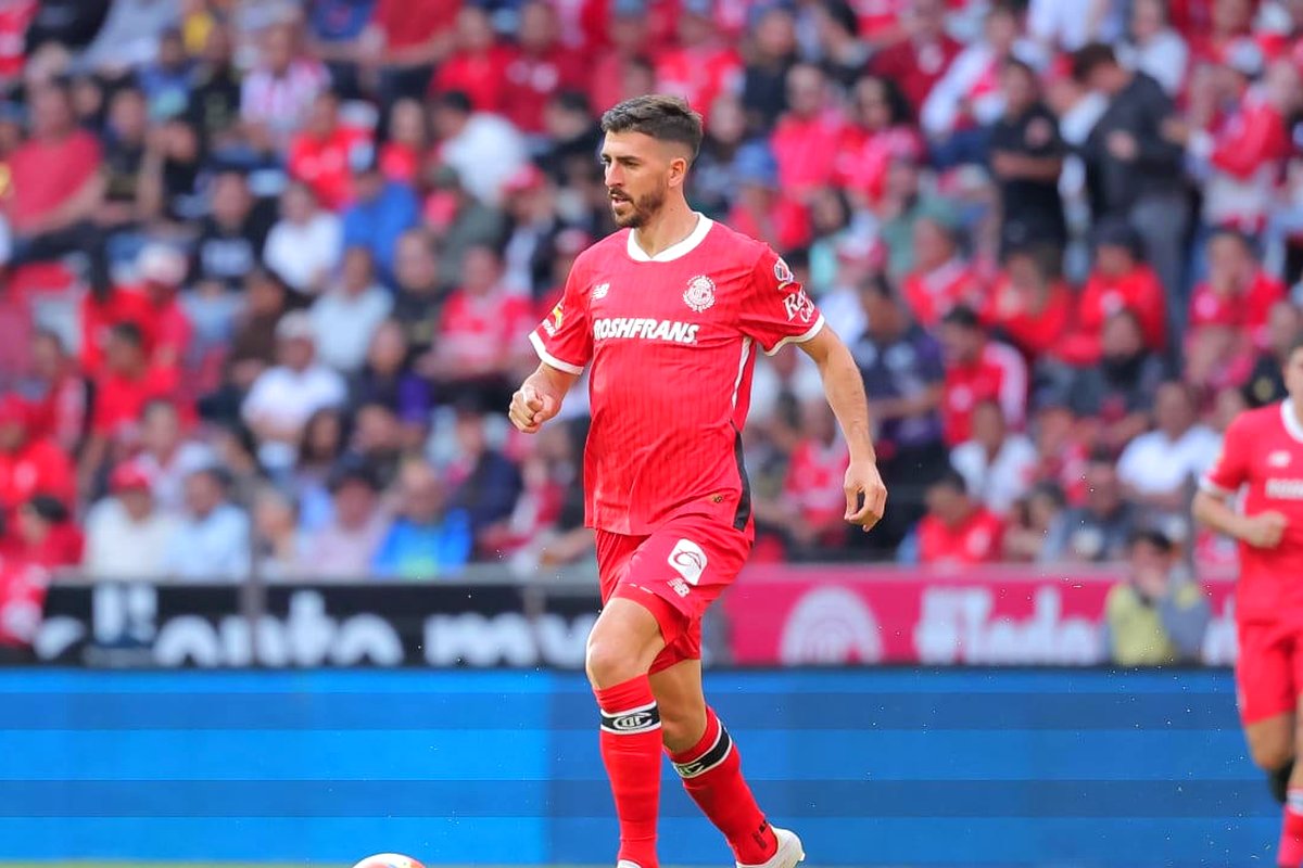 Paulinho, delantero del Toluca, con la camiseta escarlata, en acción frente a la afición