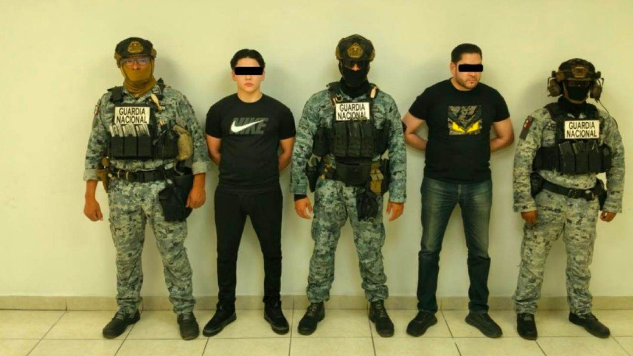 Elementos de la Guardia Nacional presentan a dos detenidos, con los ojos cubiertos