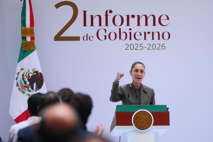 Claudia Sheinbaum en escala de grises, al podio; bandera de México y recinto a color