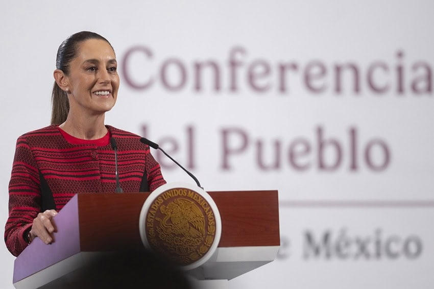 Claudia Sheinbaum, saco rojo, en el podio de la Conferencia del Pueblo, a color